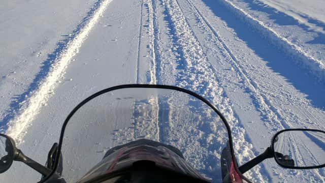 Utsikt över snö och skoterspår från snöskoter. 